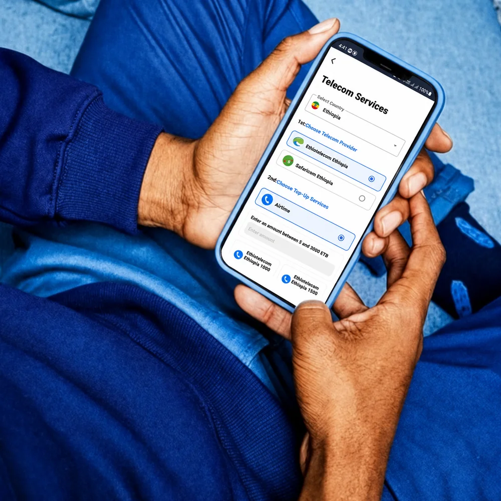 Hands holding a phone on SmilePay's Telecom Services screen with Ethiopia and Ethio Telecom selected